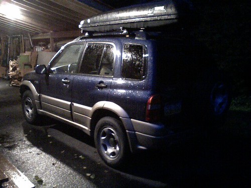 A vehicle with a rooftop cargo box mounted on crossbars, packed and ready for a road trip