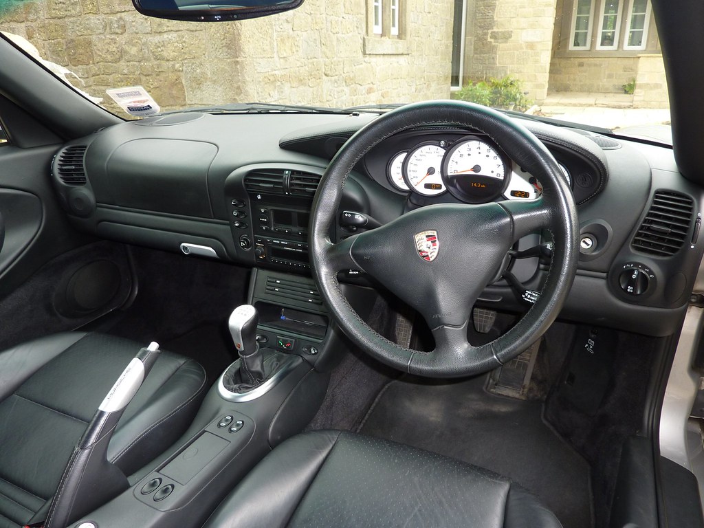 Hands cleaning a car interior surface with a cloth and spray cleaner during a detailing session