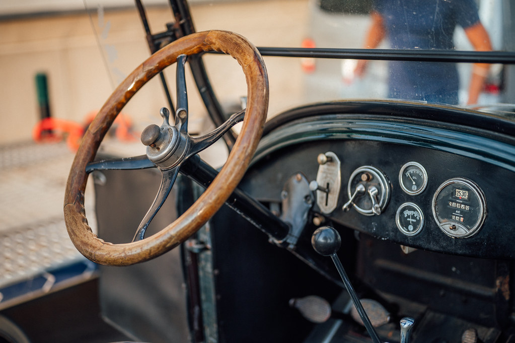 Close-up of the laminated wooden rim and metal spokes of a steering wheel in an early vintage American car