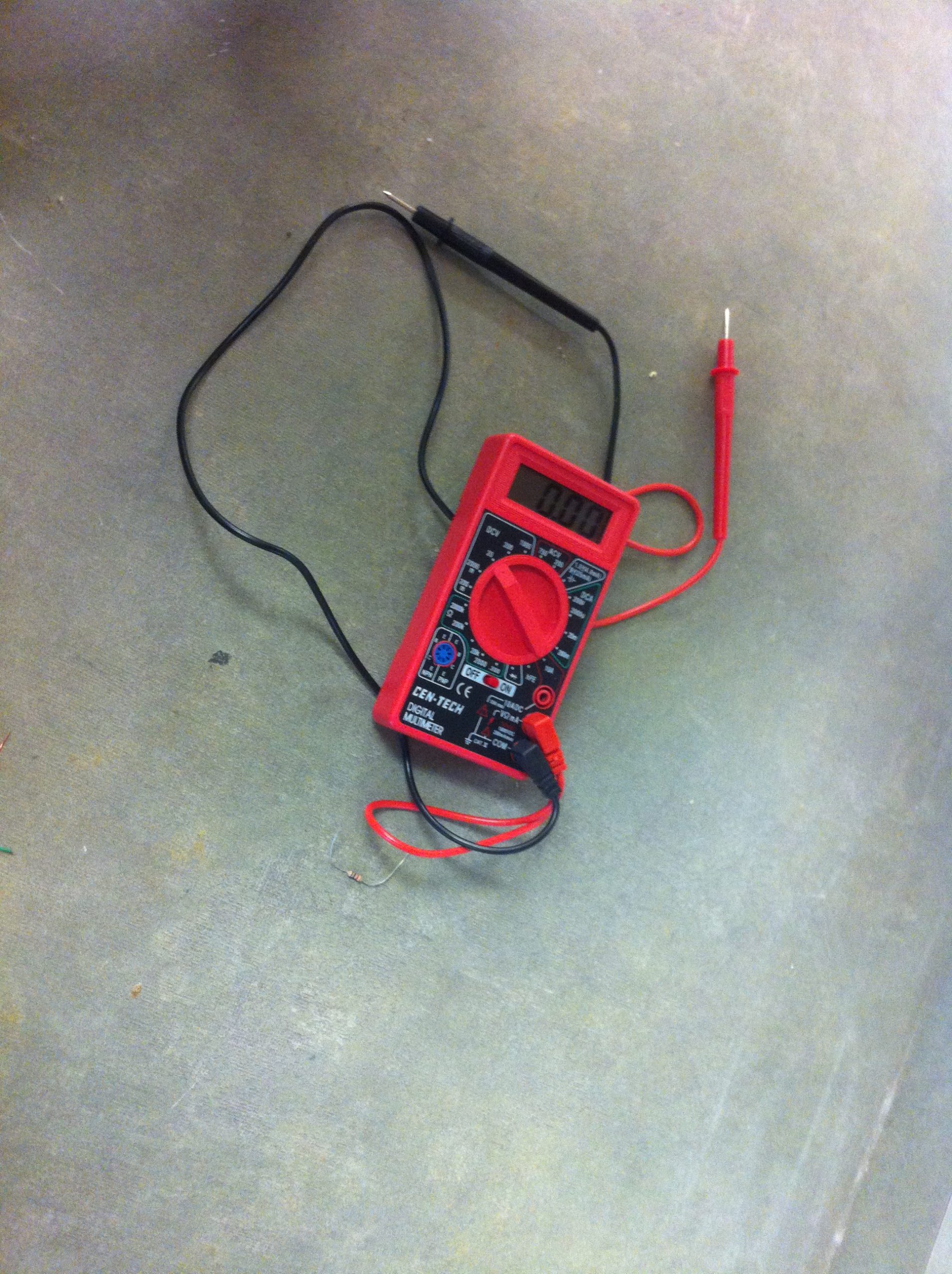 A digital multimeter used for measuring battery voltage.