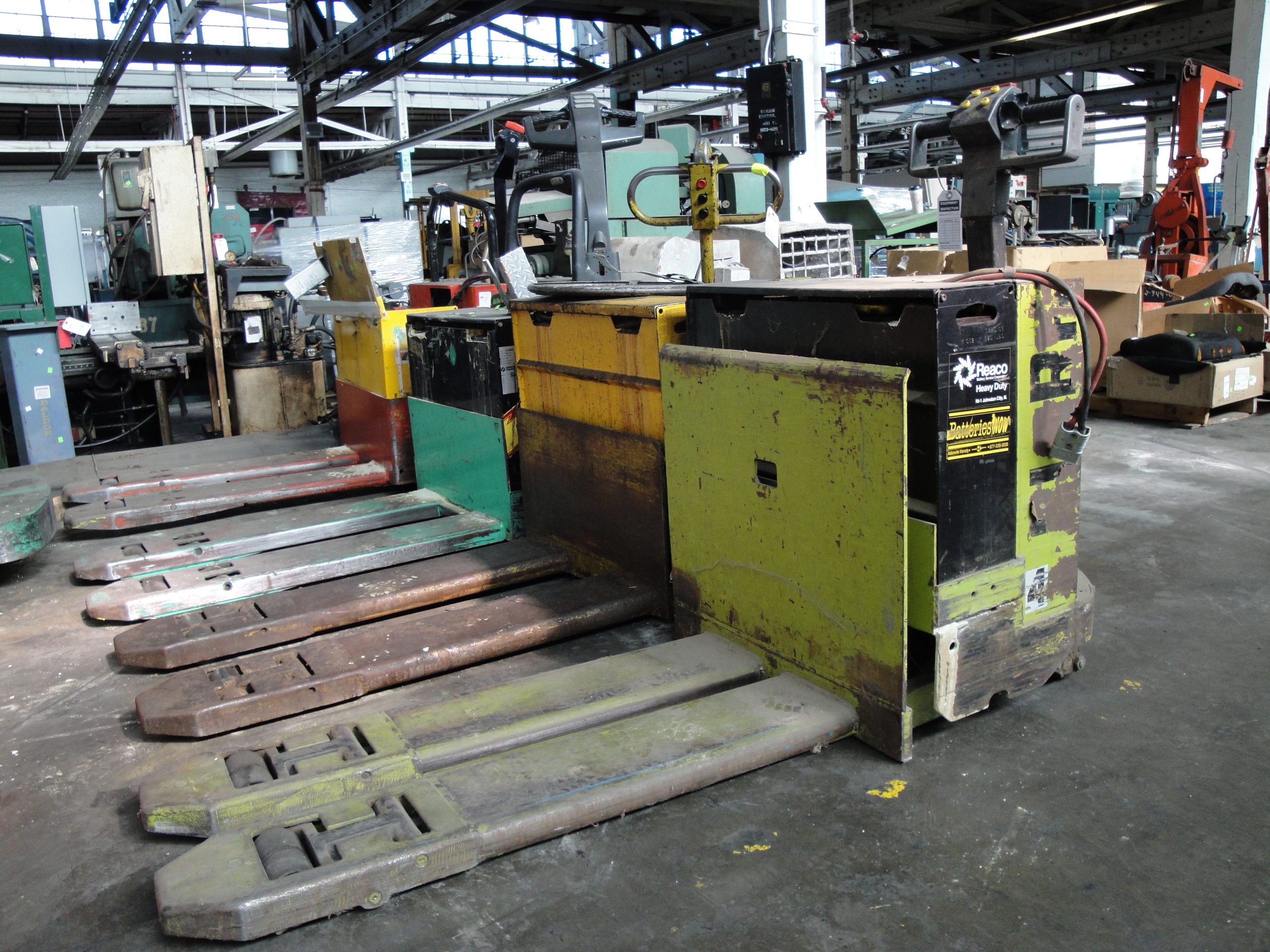 An electric pallet jack with charging cable in a warehouse setting.