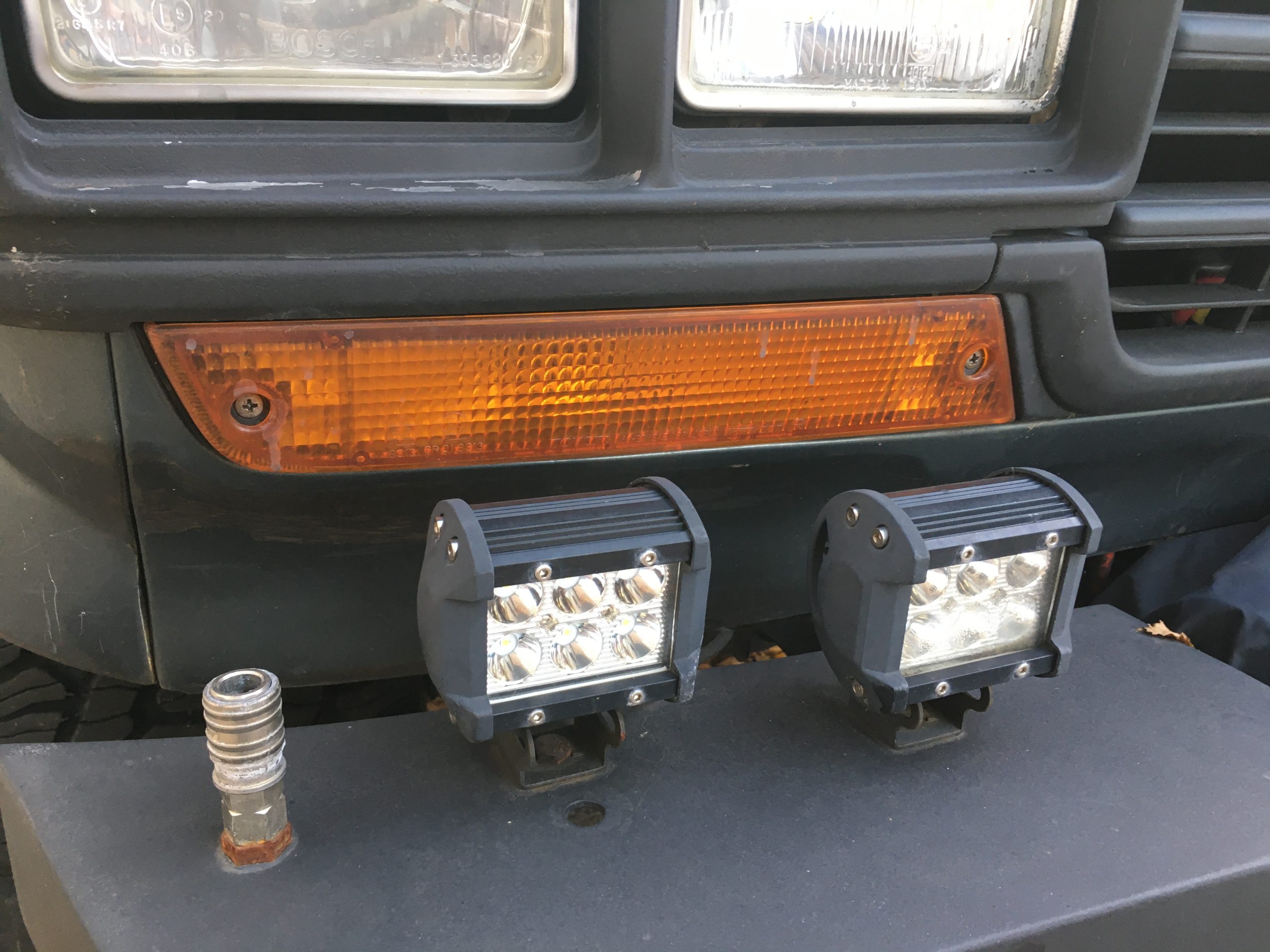 Toyota Land Cruiser front bumper equipped with auxiliary LED driving lights alongside factory headlights.