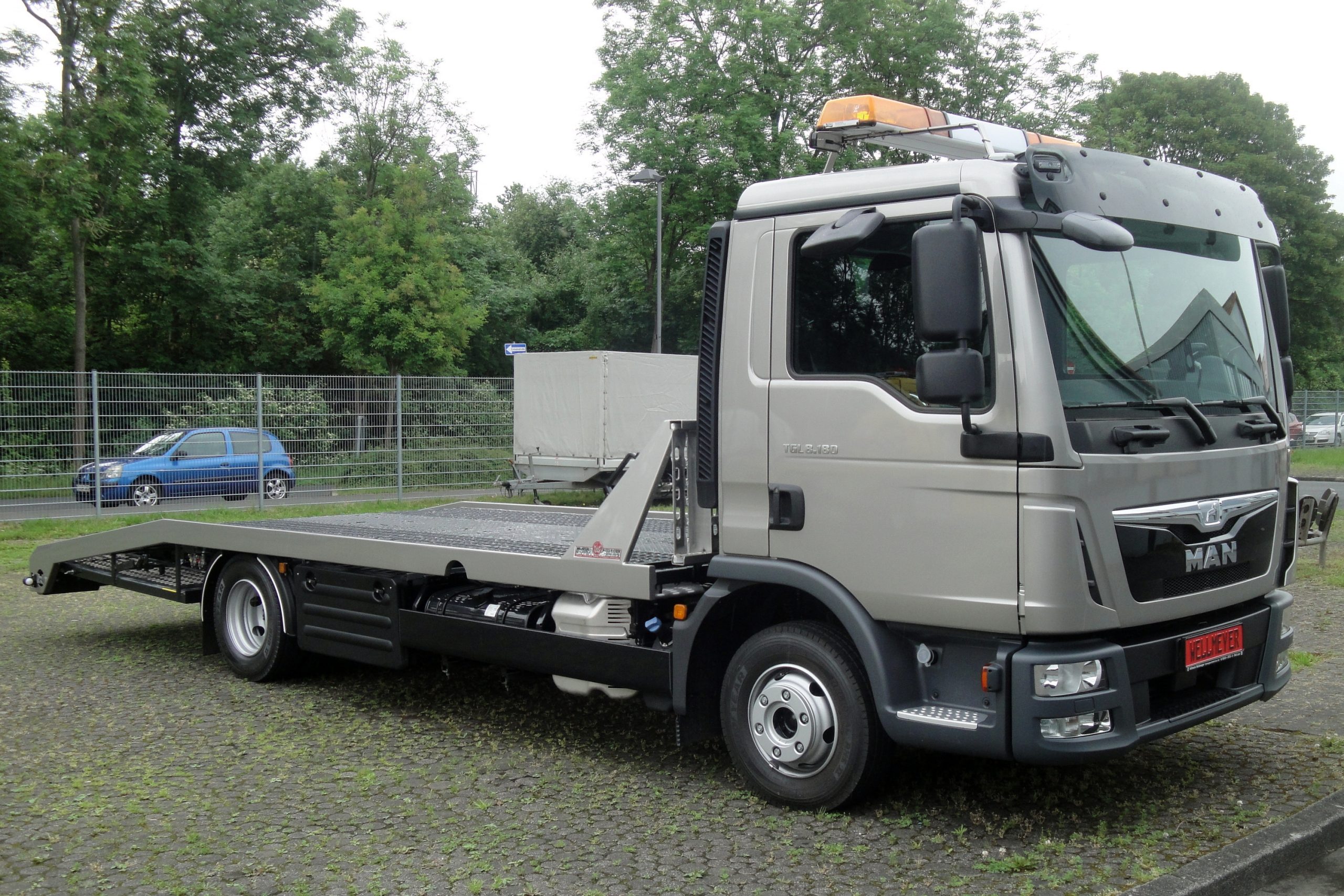 Flatbed tow truck equipped with an amber roof-mounted warning light bar.