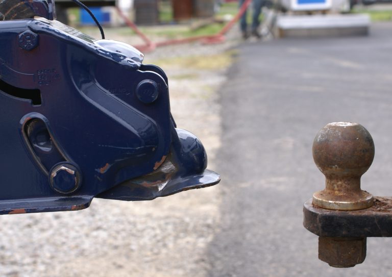 Close-up of a trailer hitch ball and coupler mount on a towing vehicle.