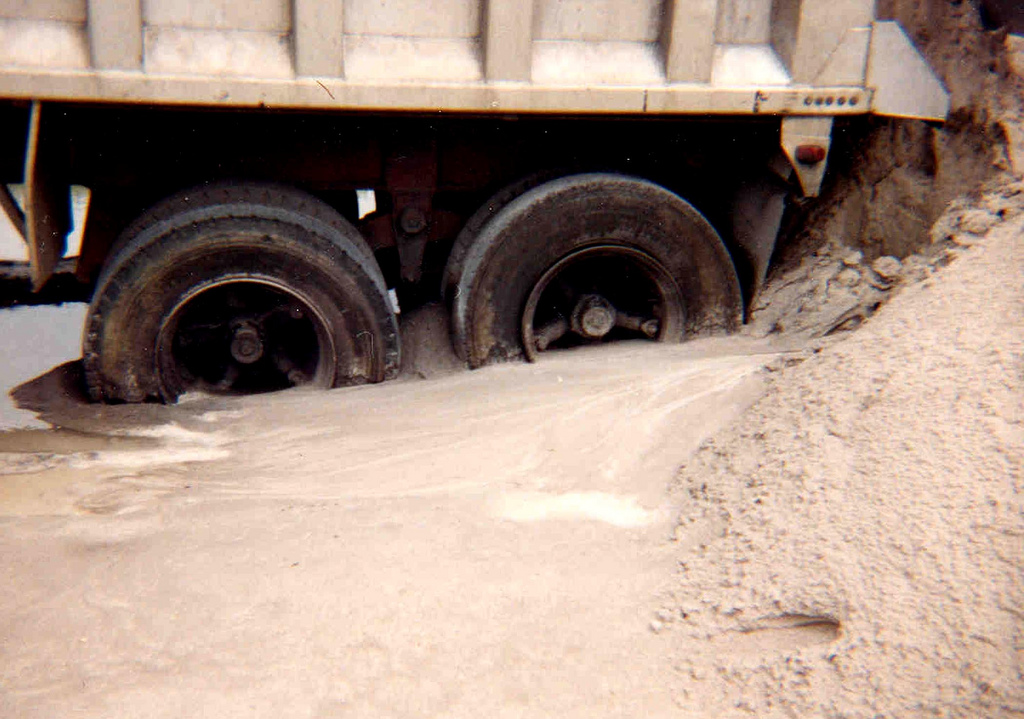 A truck stuck deep in mud, the kind of off-road recovery scenario where a triple bag air jack is used.