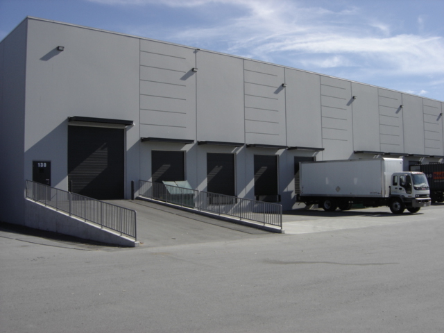 A warehouse loading dock where pallet jacks and forklifts load and unload trailers.
