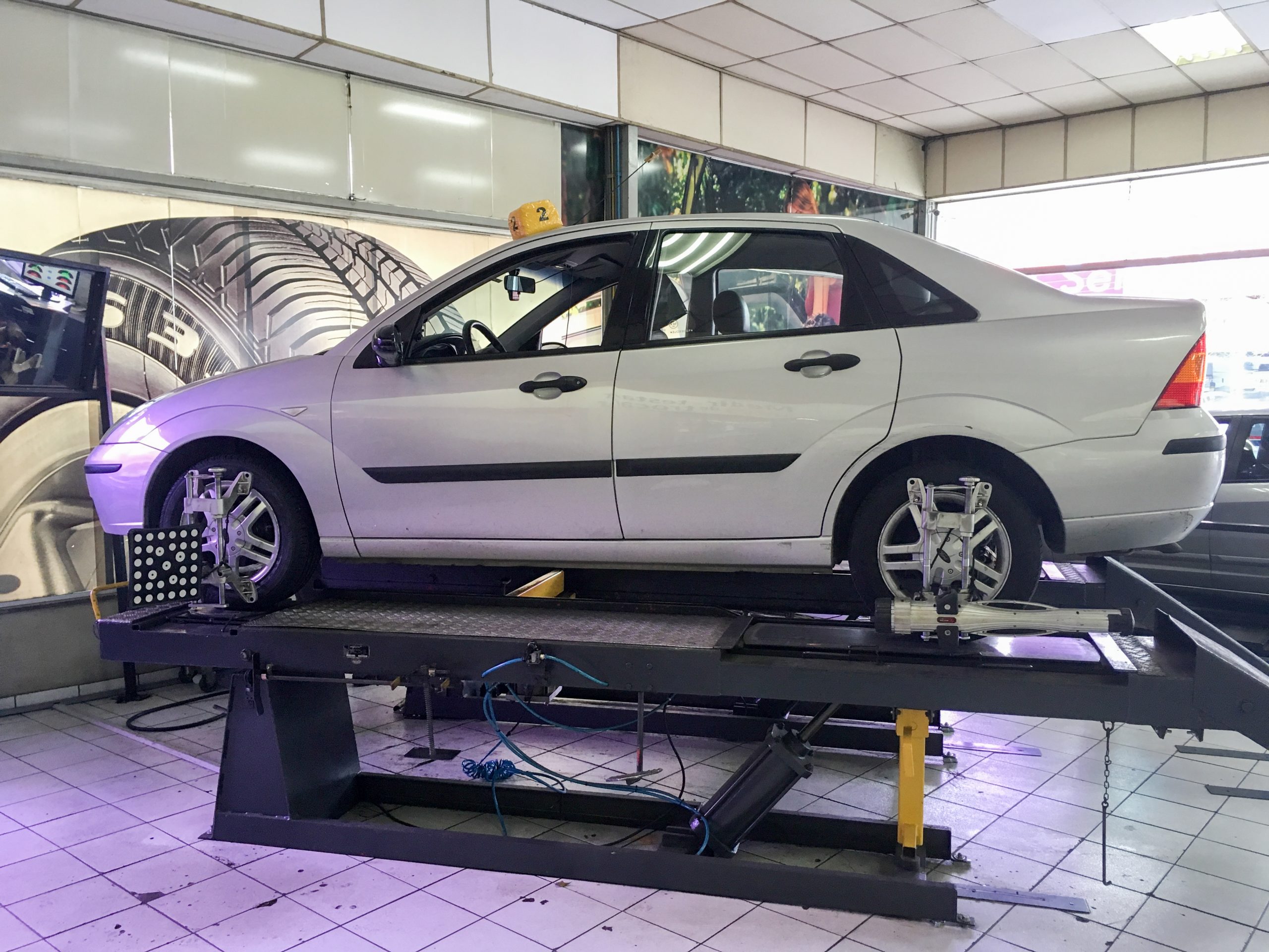 A Ford Focus raised on a two-post automotive lift during a wheel alignment service.