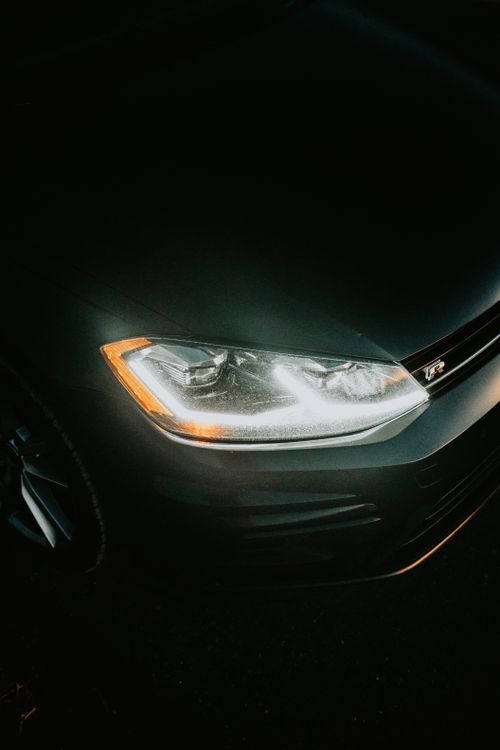 Close-up of an illuminated vehicle headlight glowing in the dark, showing beam intensity at night.