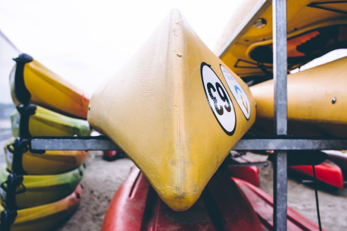 Closeup of a yellow kayak resting on a gray metal storage rack.