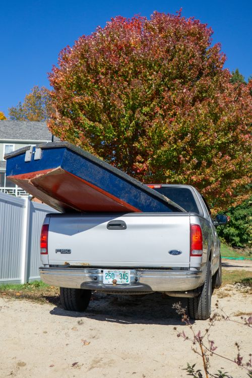Silver pickup truck hauling cargo in its open bed, demonstrating the kind of heavy-load use a bed mat is built to protect against.