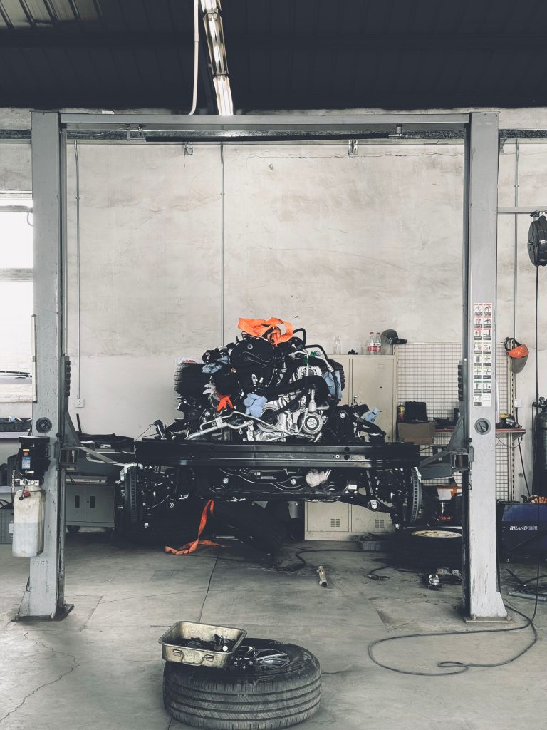Interior of an auto repair workshop showing a vehicle lift with an engine, illustrating a shop setting where an engine cradle would be used.
