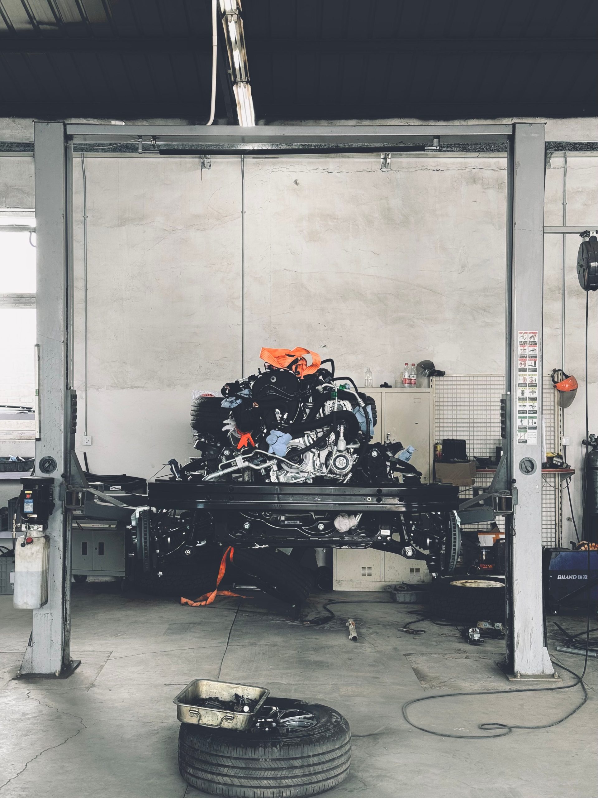 Interior of an auto repair workshop showing a vehicle lift with an engine, illustrating a shop setting where an engine cradle would be used.