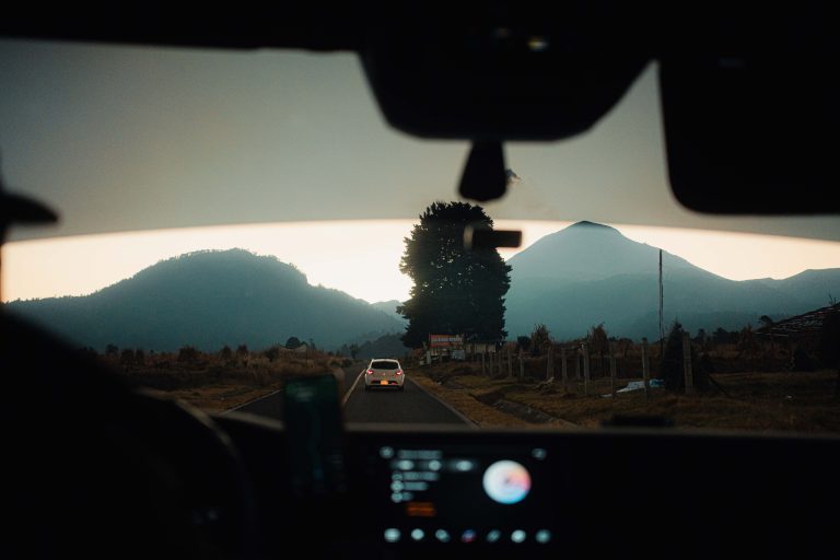 Car driving on a scenic mountain road during a summer road trip.