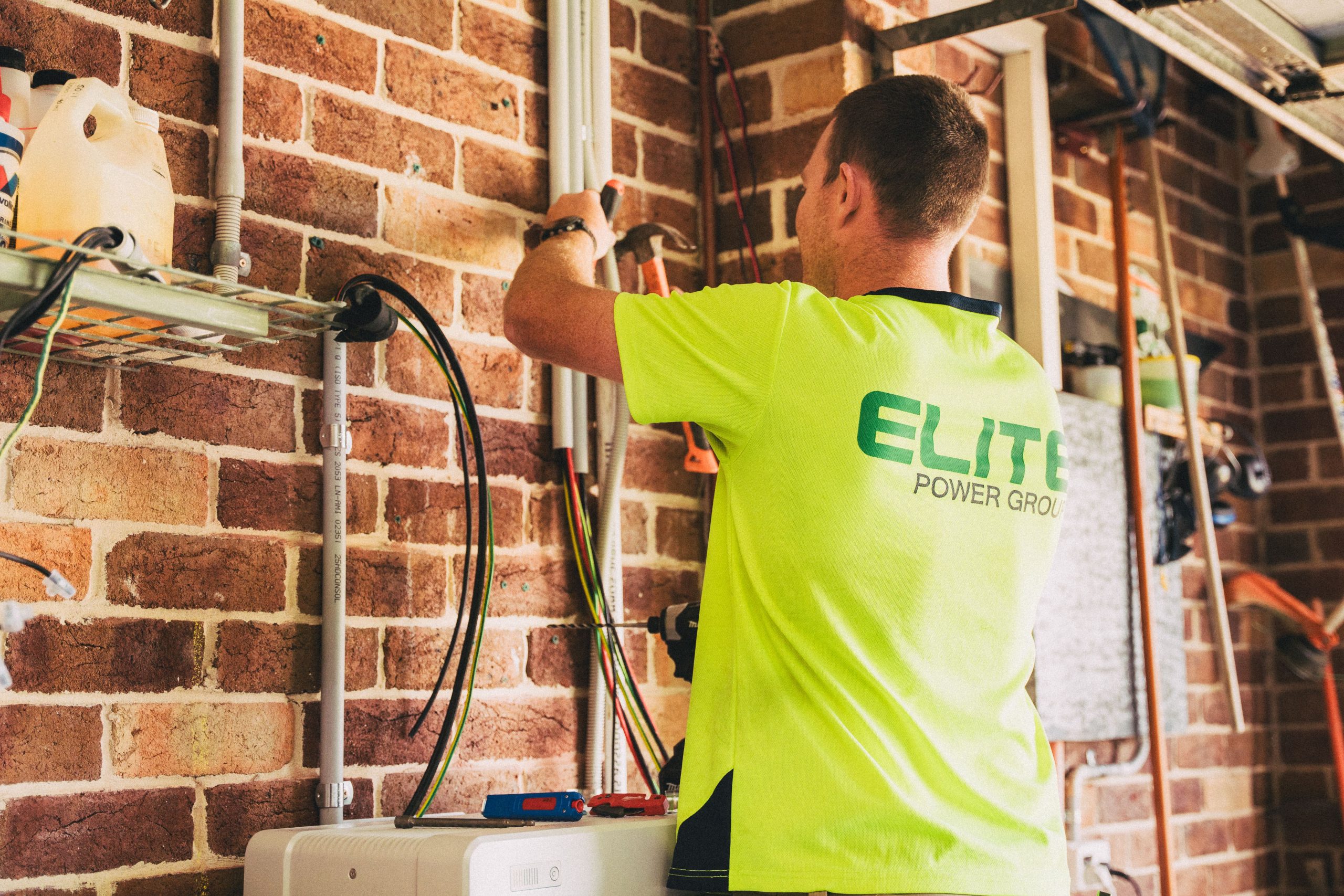 Electrician wiring a solar battery bank installation, similar to an RV house-battery inverter setup.